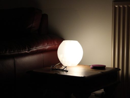 Moderne glazen salontafel in een lichte woonkamer met een grijze bank en een naturel houten vloer