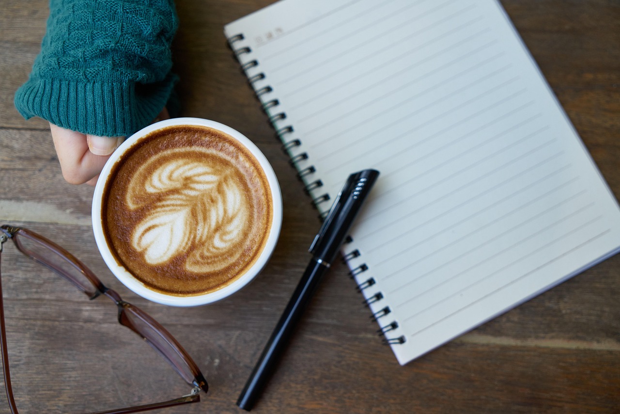 Vrouw schrijft in notitieboekje aan tafel met kop koffie tijdens ochtendrutine